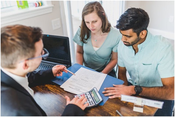 a real estate expert meeting with two people and going over contracts